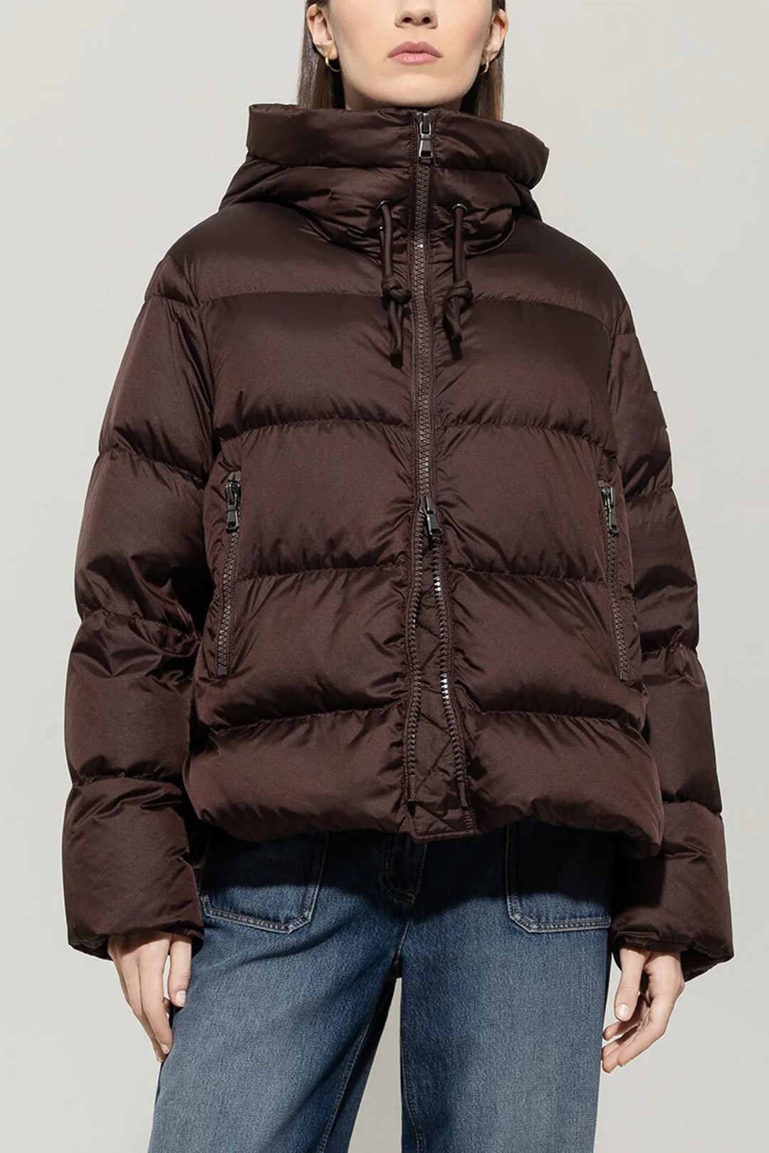 Brown puffer jacket worn by a person on a plain background