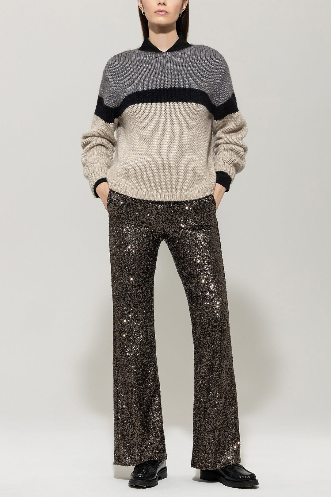Person wearing a two-tone sweater and sparkly pants on a white background