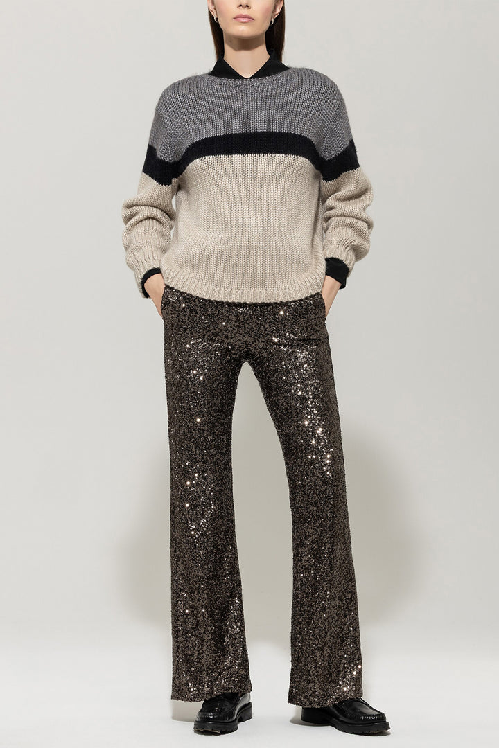 Person wearing a two-tone sweater and sparkly pants on a white background