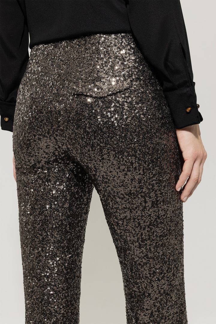 Person wearing black sequin pants with a plain background