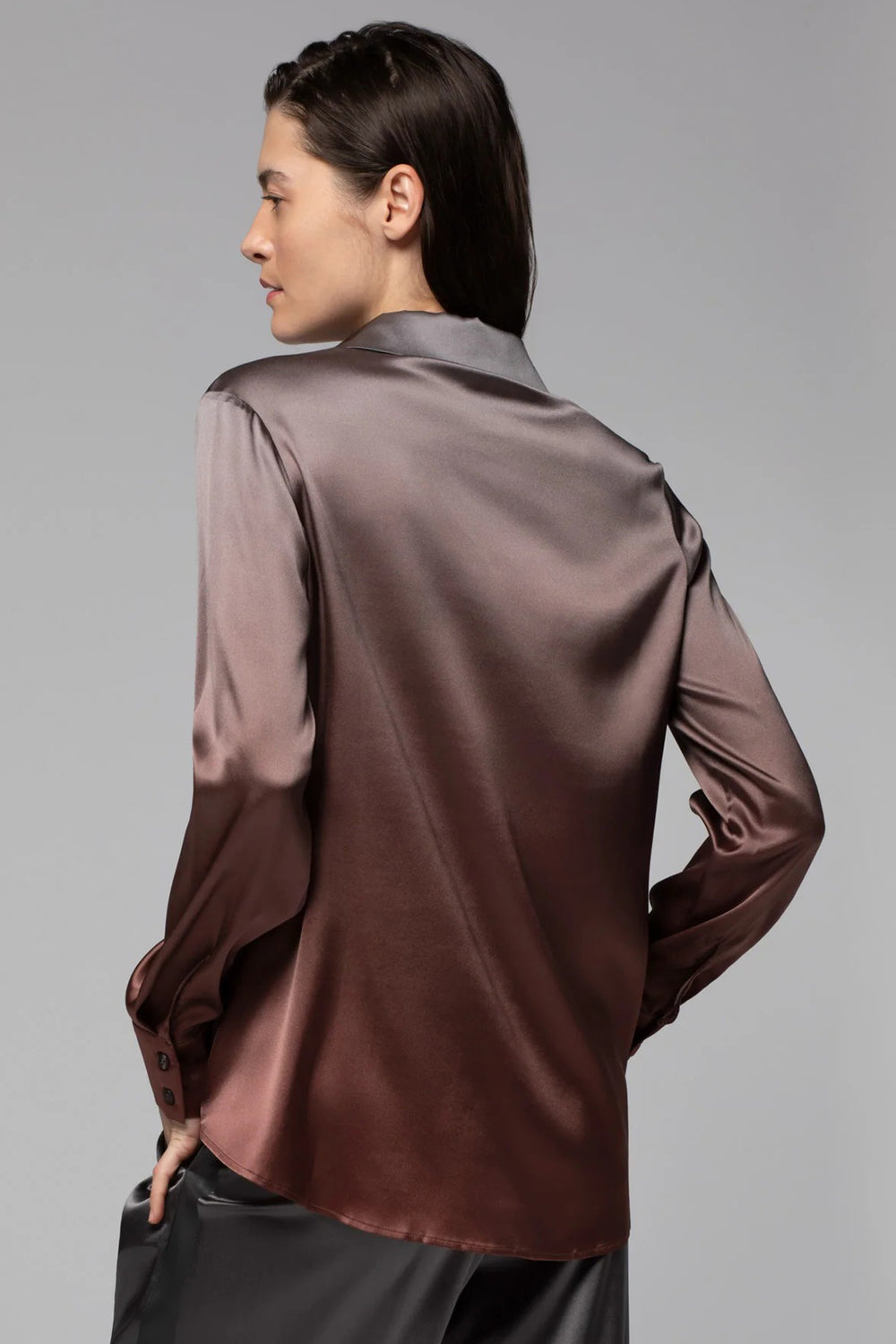 Person wearing a brown satin shirt against a gray background