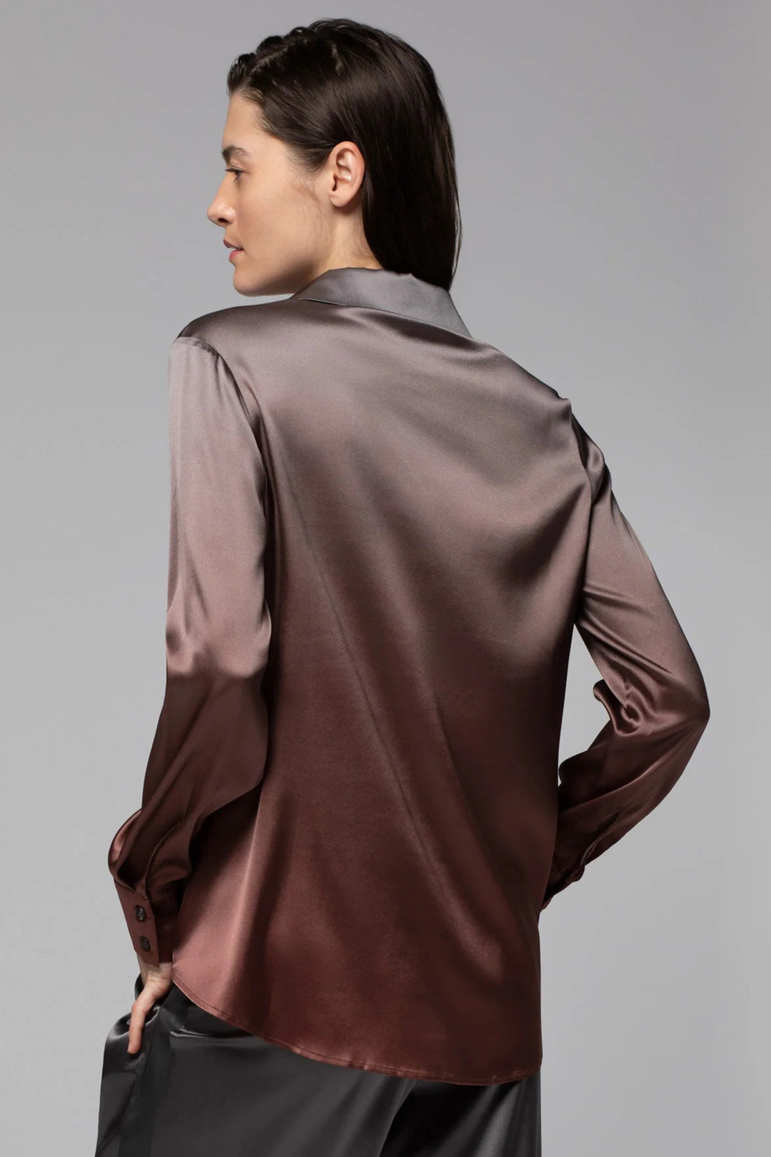 Person wearing a brown satin shirt against a gray background