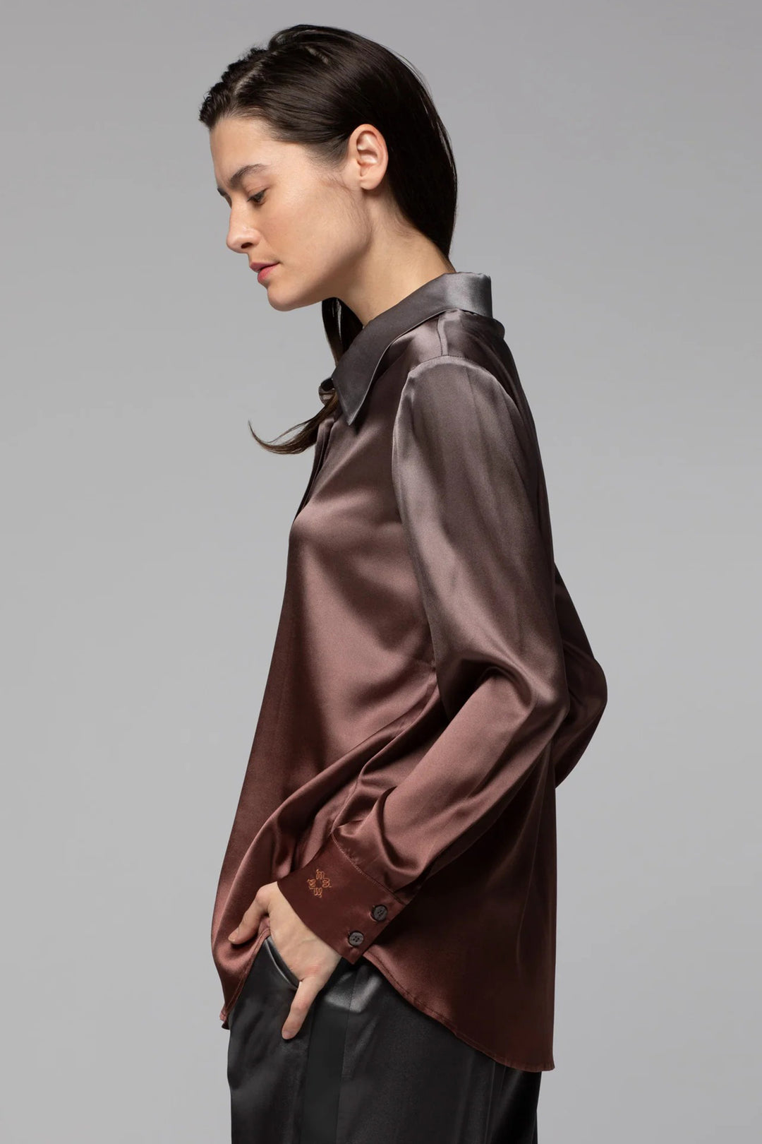 Woman wearing a brown satin shirt against a gray background