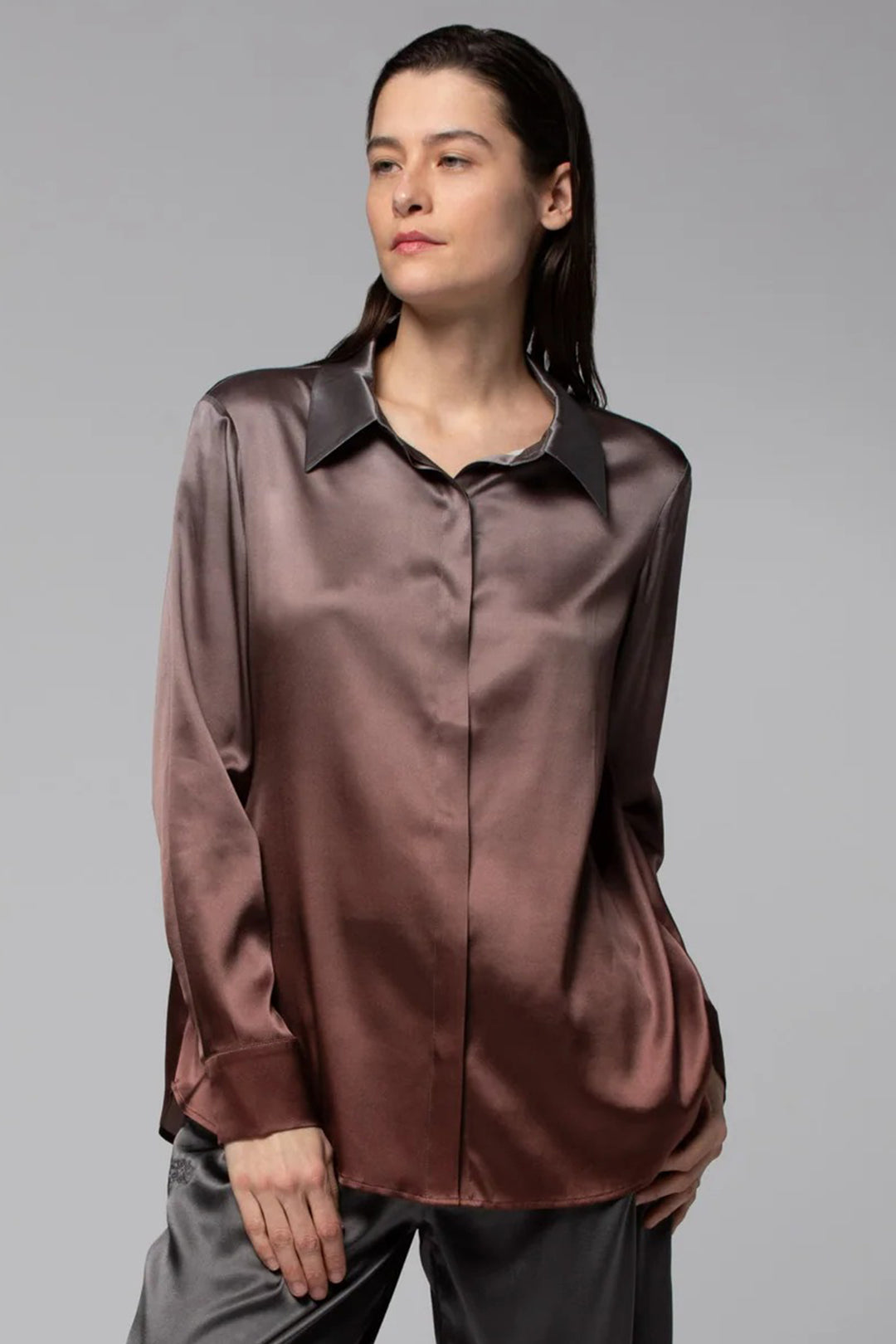 Woman wearing a brown satin shirt against a gray background