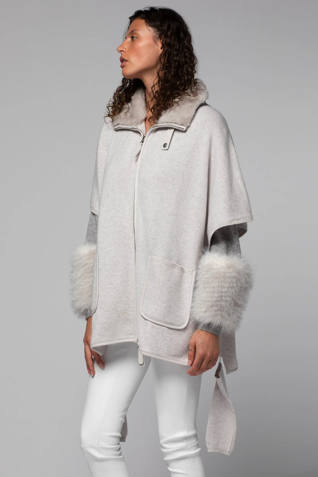 Woman wearing a gray coat with fur trim on a gray background