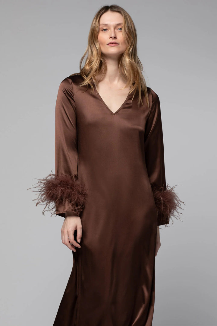 Woman wearing a brown satin dress with feathered sleeves on a gray background