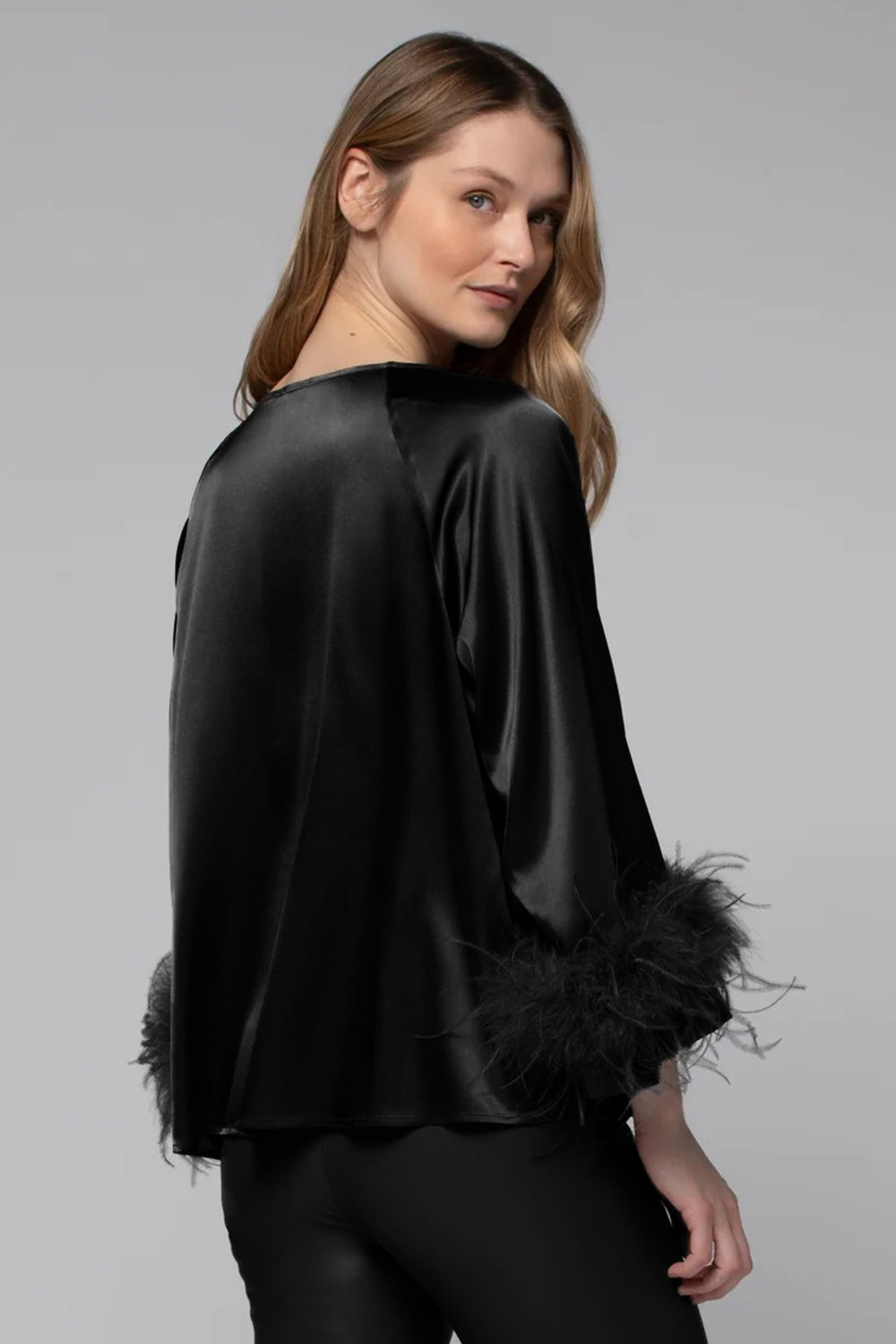 Black silk blouse with feathered cuffs on a gray background