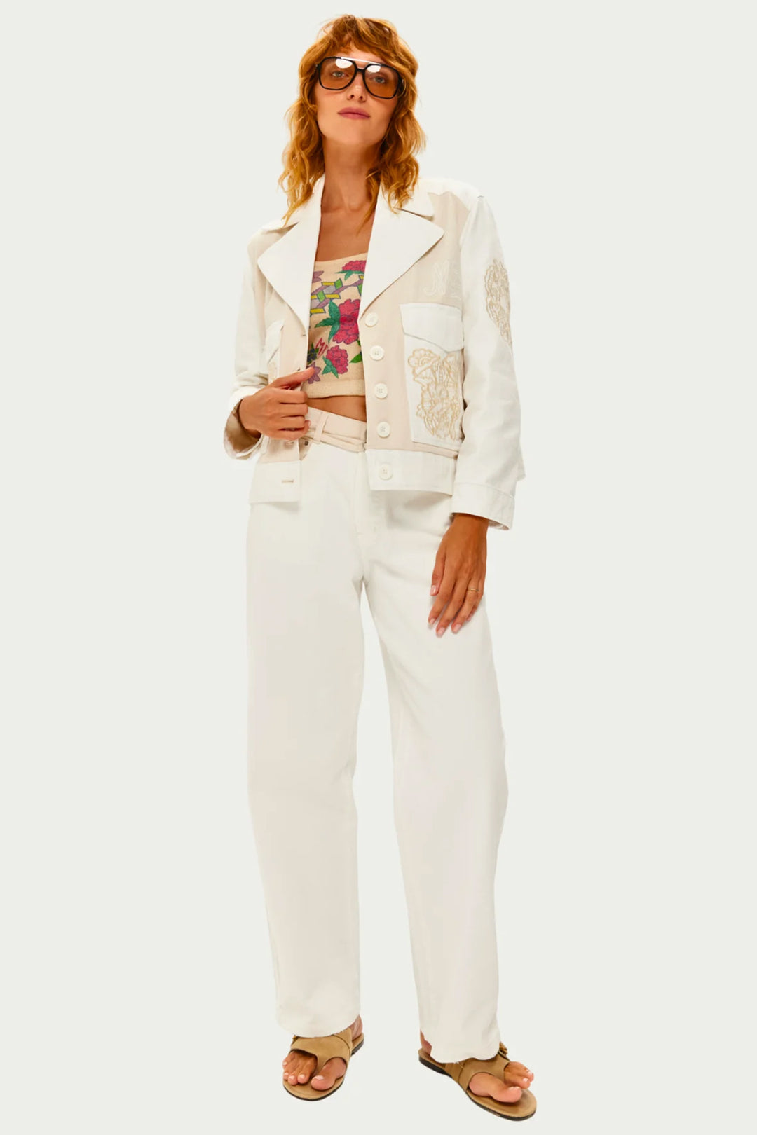 Woman wearing a white jacket and pants with a floral top on a white background