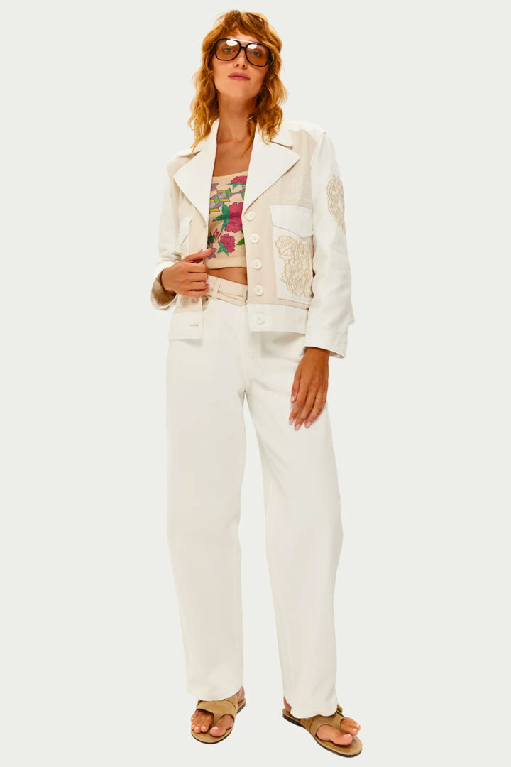Woman wearing a white jacket and pants with a floral top on a white background