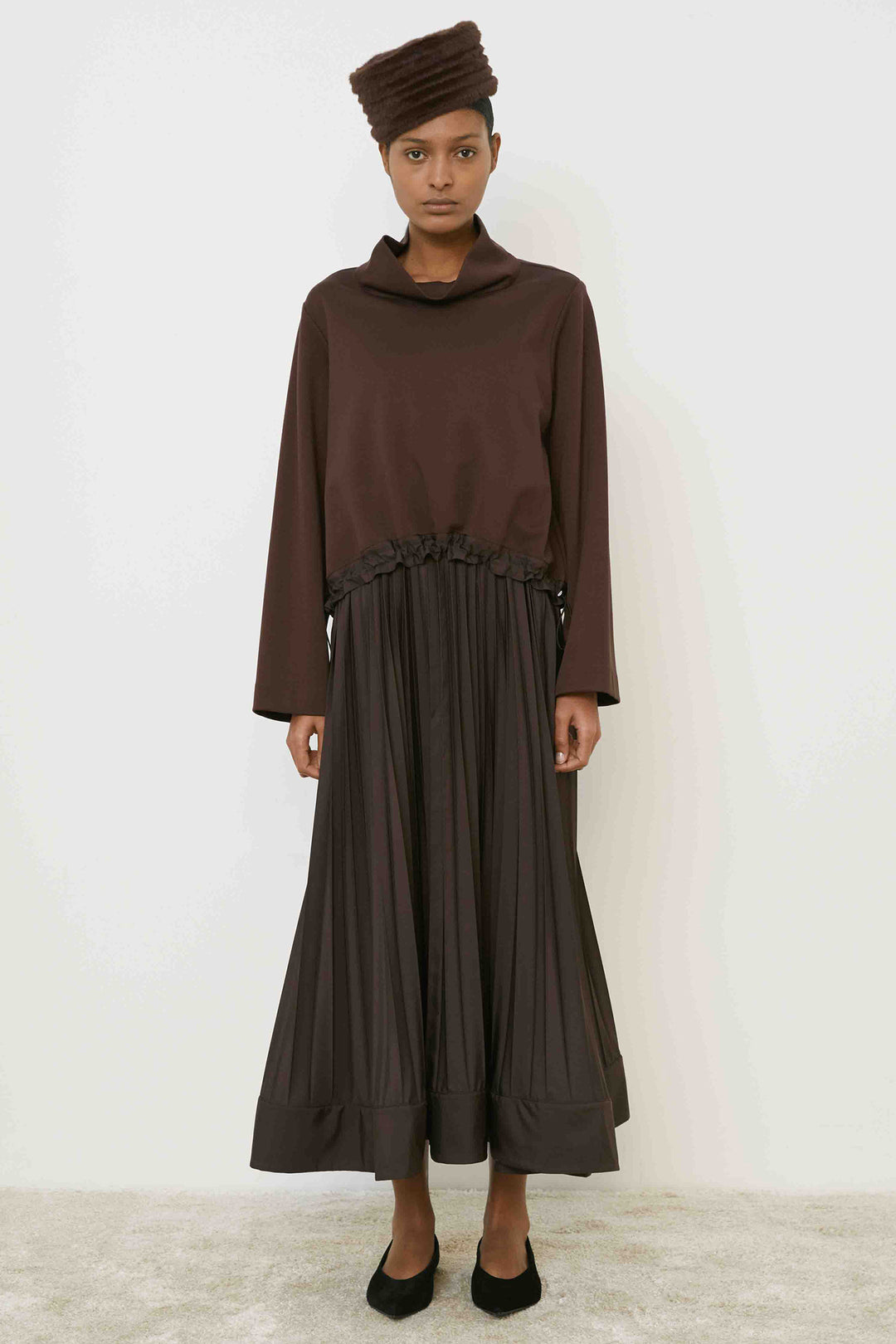Woman wearing a brown outfit with a matching headscarf on a white background