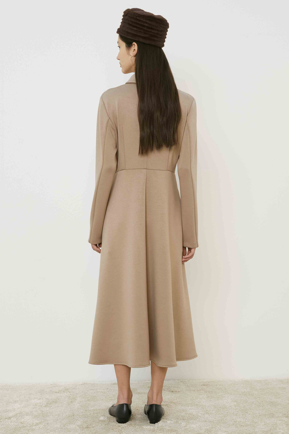 Woman wearing a beige dress and headscarf on a white background