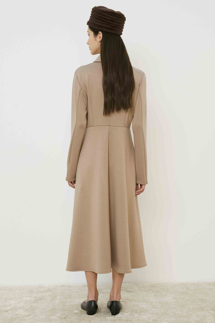 Woman wearing a beige dress and headscarf on a white background