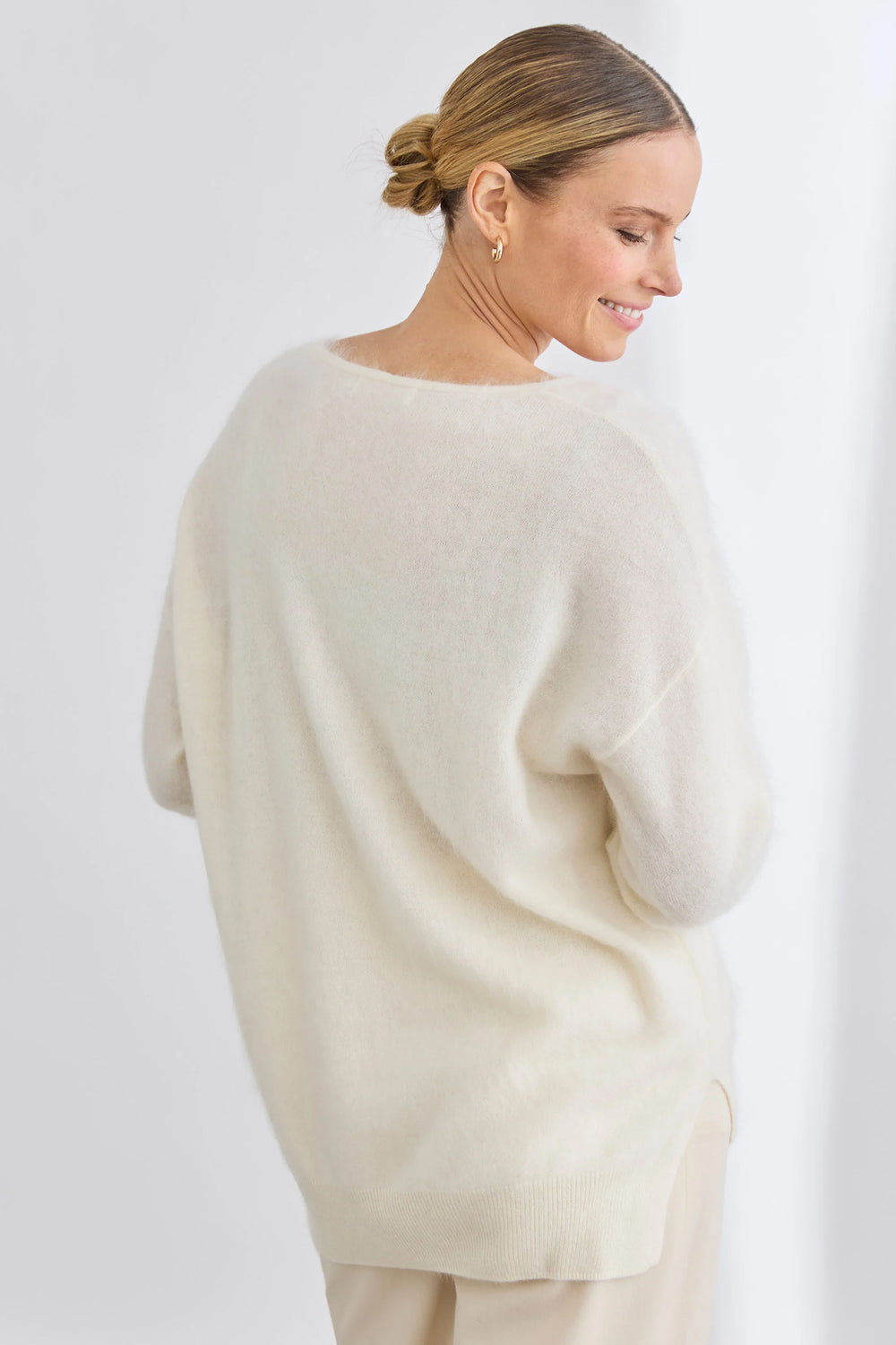 Woman wearing a cream sweater and pants against a white background