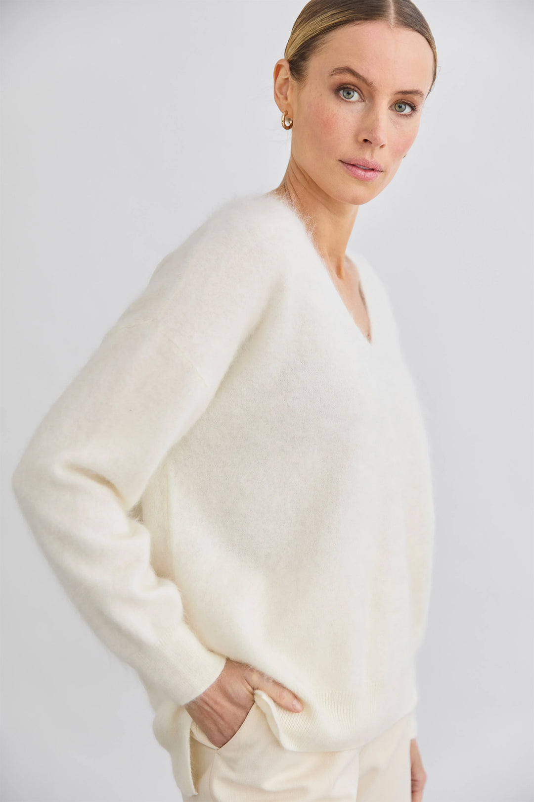 Woman wearing a white sweater against a plain background