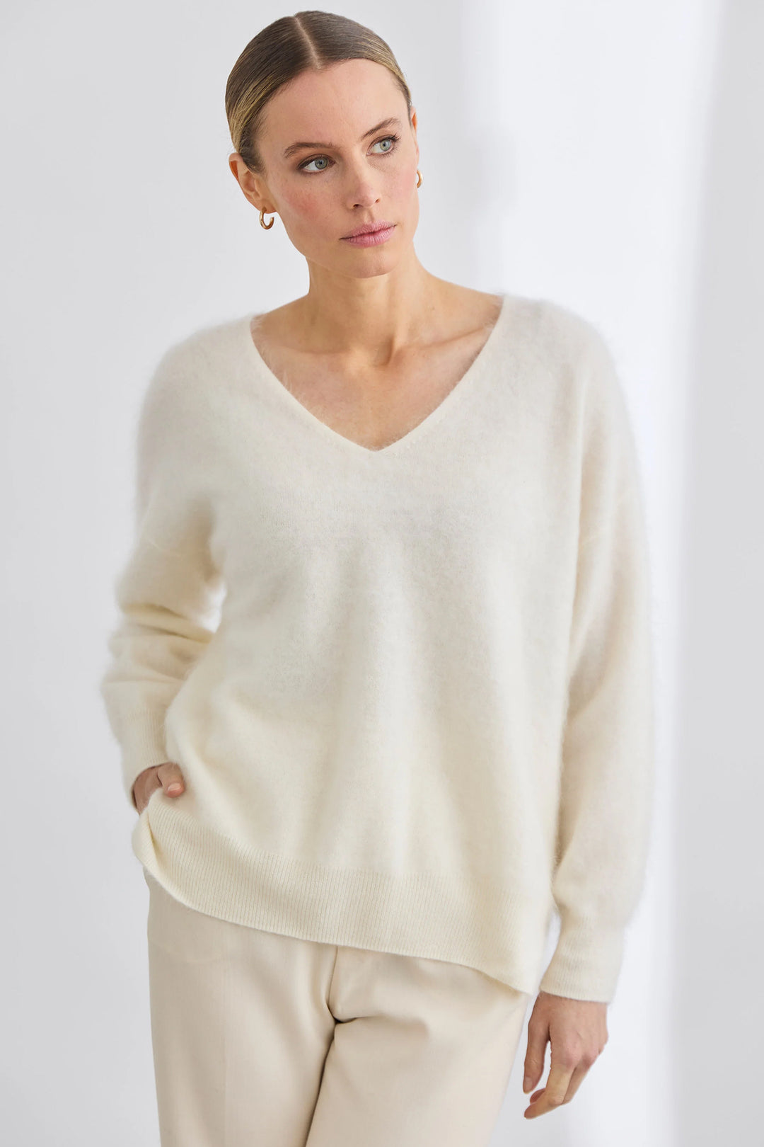 Woman wearing a cream-colored sweater against a white background
