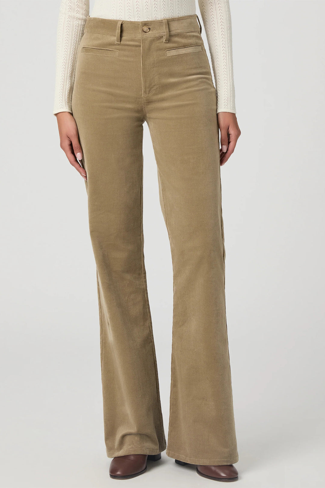 Beige corduroy pants worn by a person on a white background