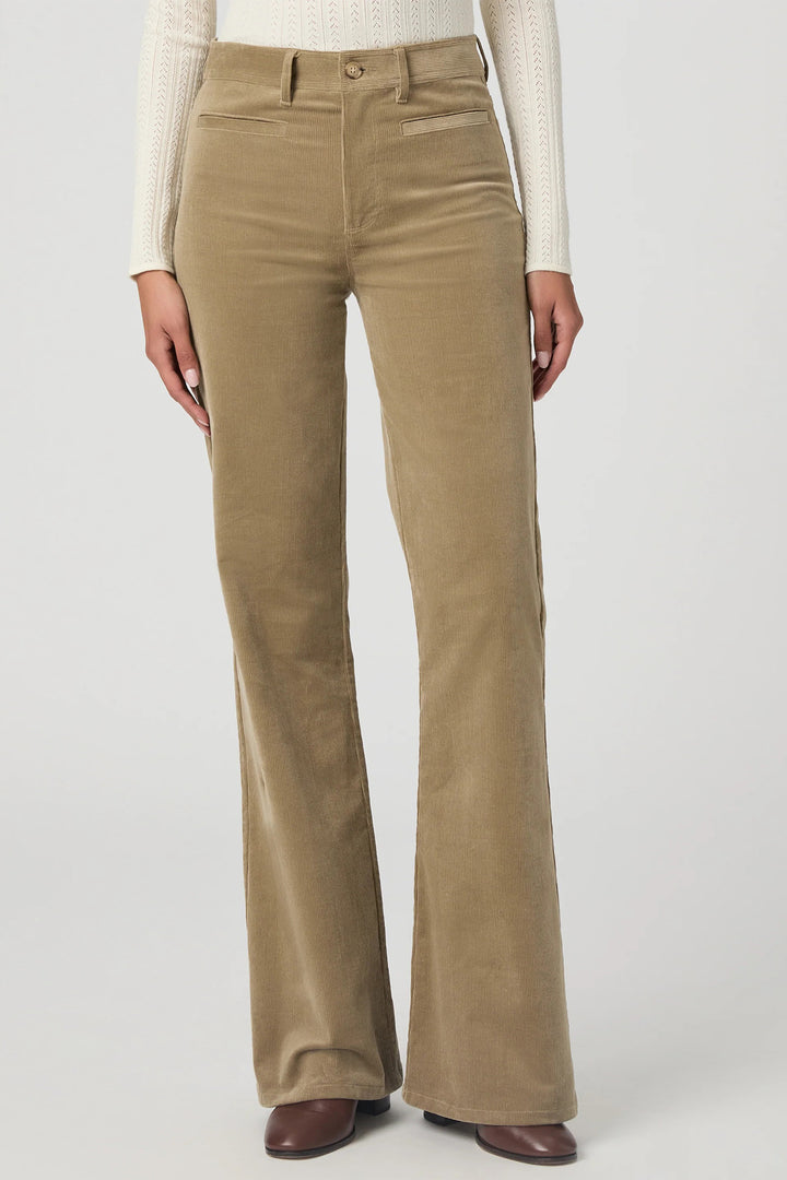 Beige corduroy pants worn by a person on a white background
