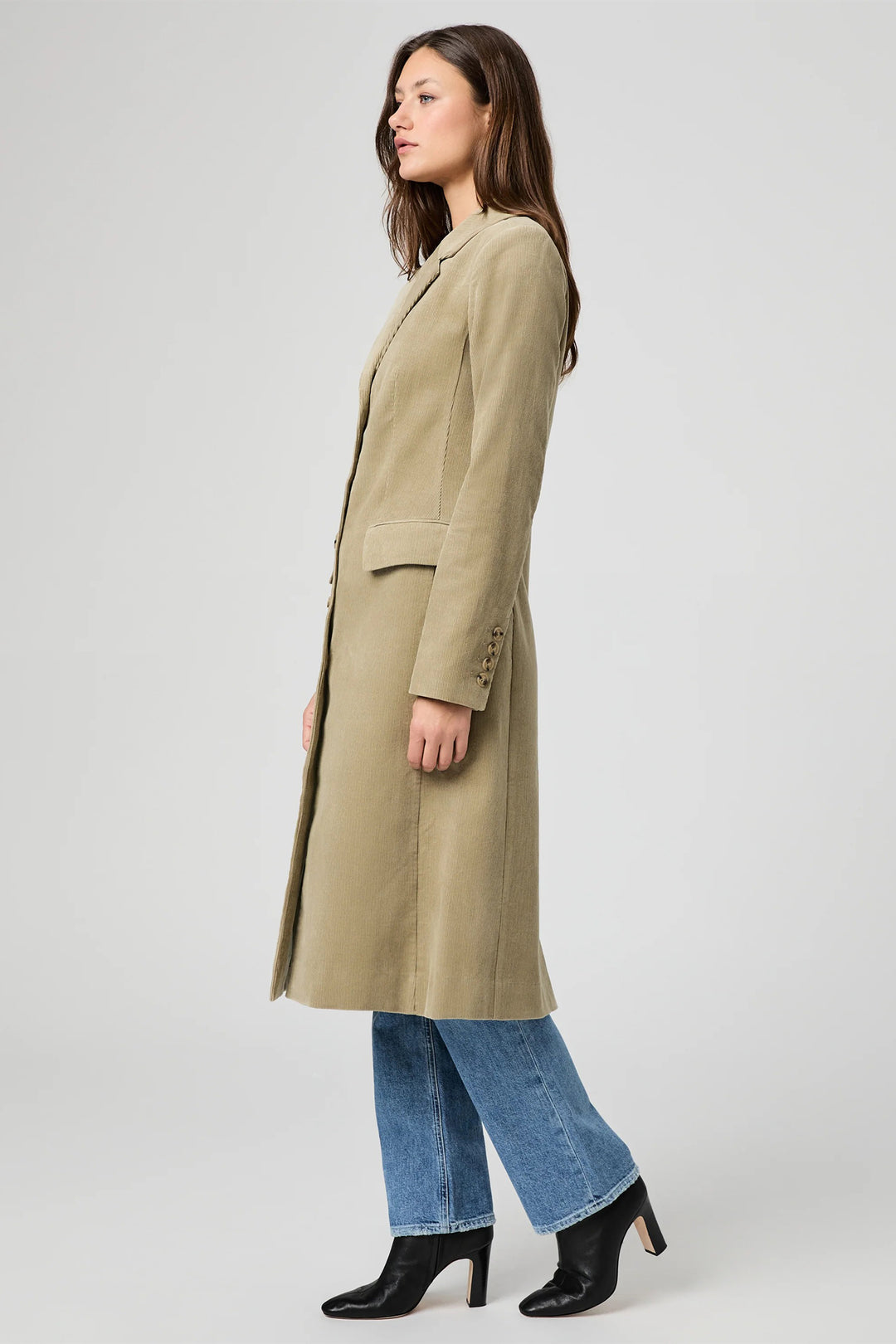 Woman wearing a long beige coat on a white background