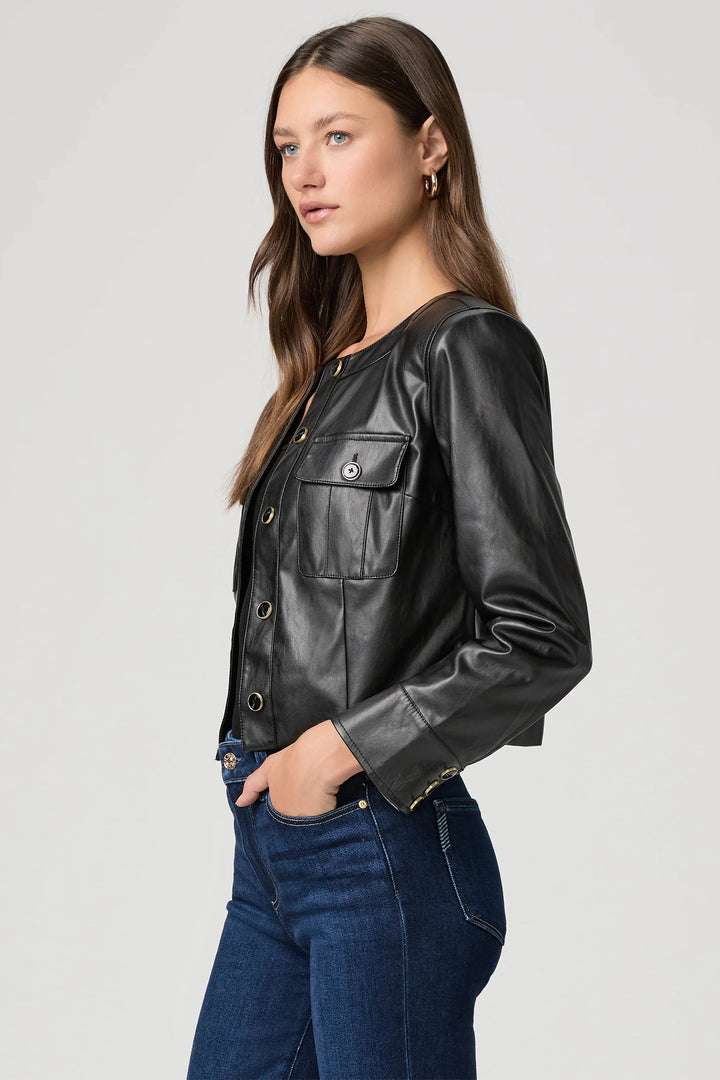 Woman wearing a black leather jacket and blue jeans on a light gray background