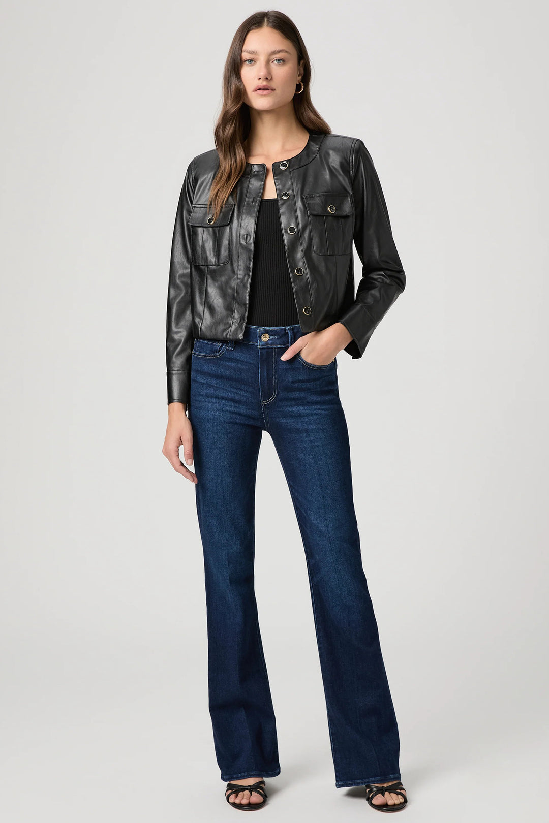 Woman wearing a black leather jacket and blue jeans on a white background