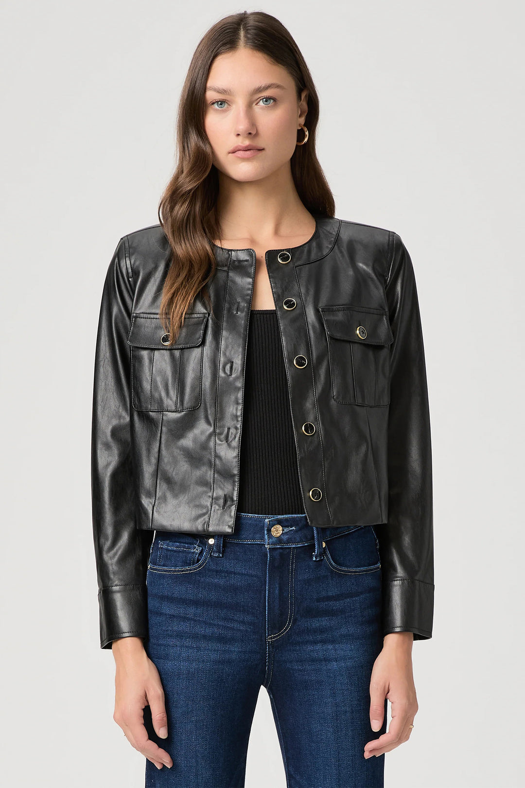 Woman wearing a black leather jacket and blue jeans on a white background