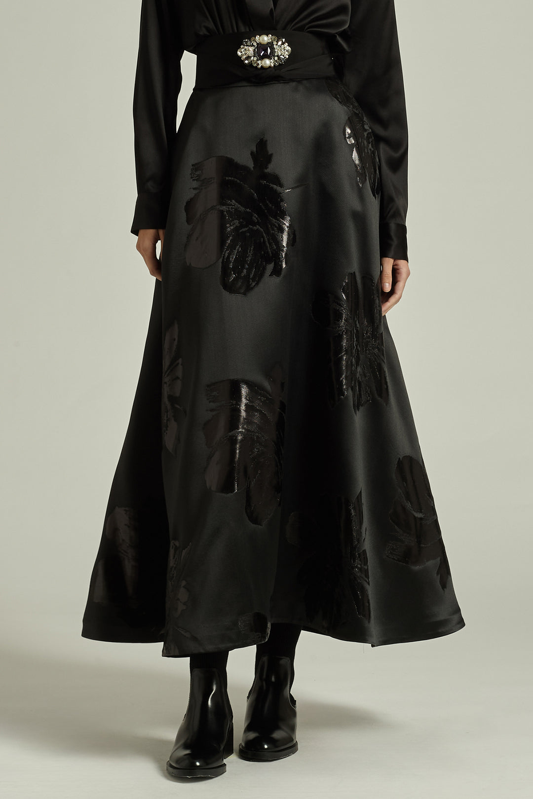 Black skirt with floral appliqués worn by a person on a neutral background