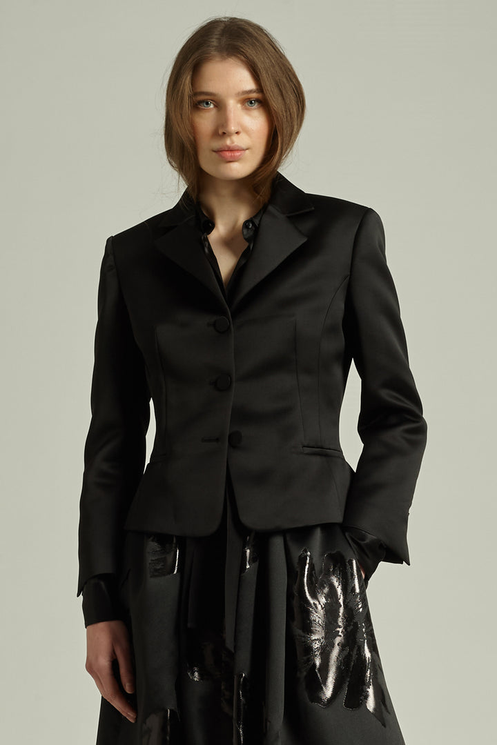 Woman wearing a black suit with a plain background