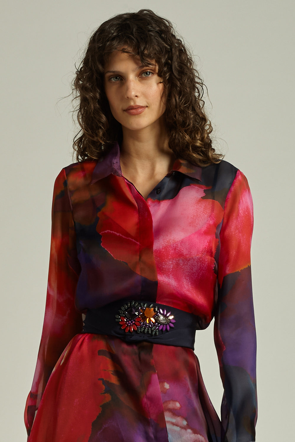 Woman wearing a colorful, patterned dress with a plain background