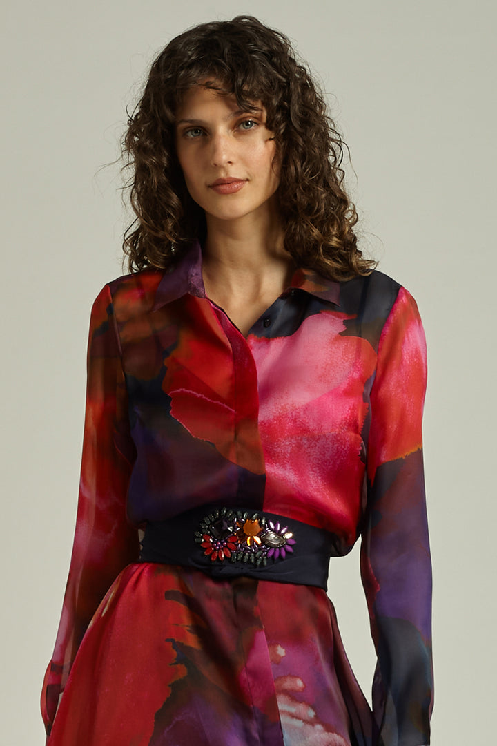 Woman wearing a colorful, patterned dress with a plain background