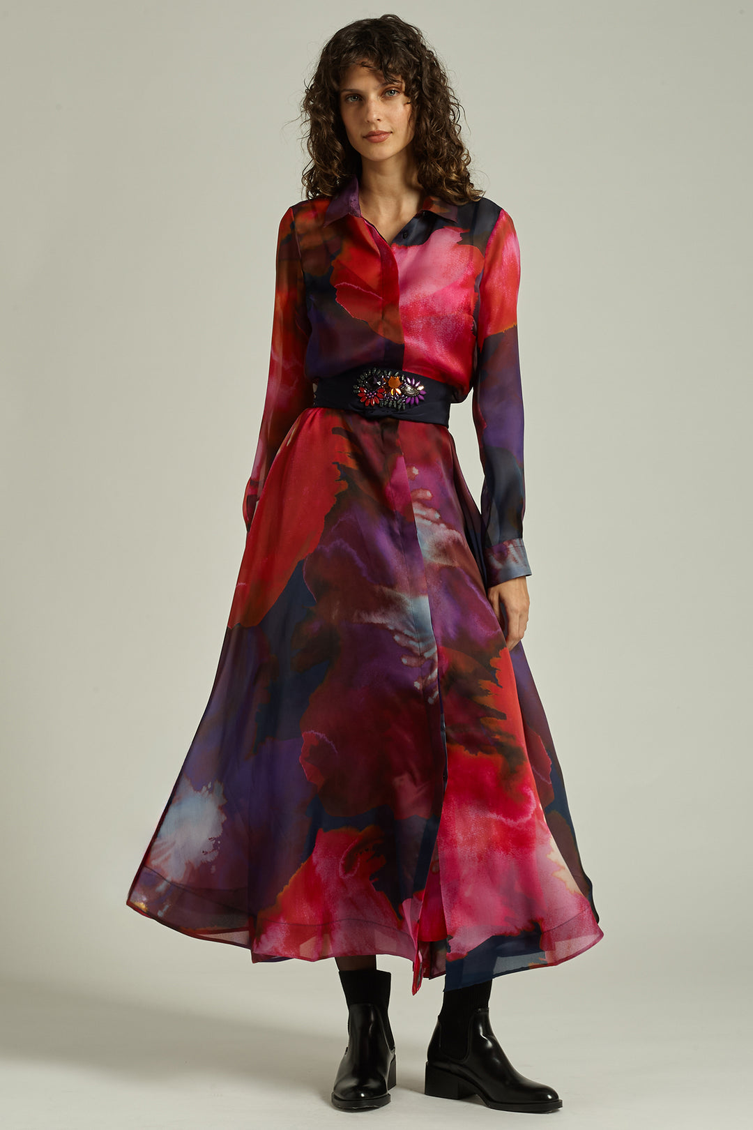 Woman wearing a colorful dress with a belt on a plain background