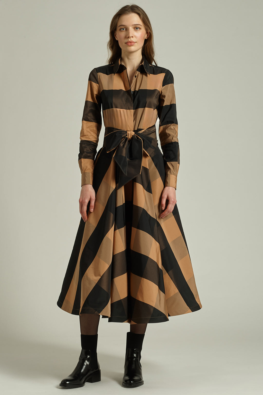 Woman wearing a brown and black striped dress on a plain background