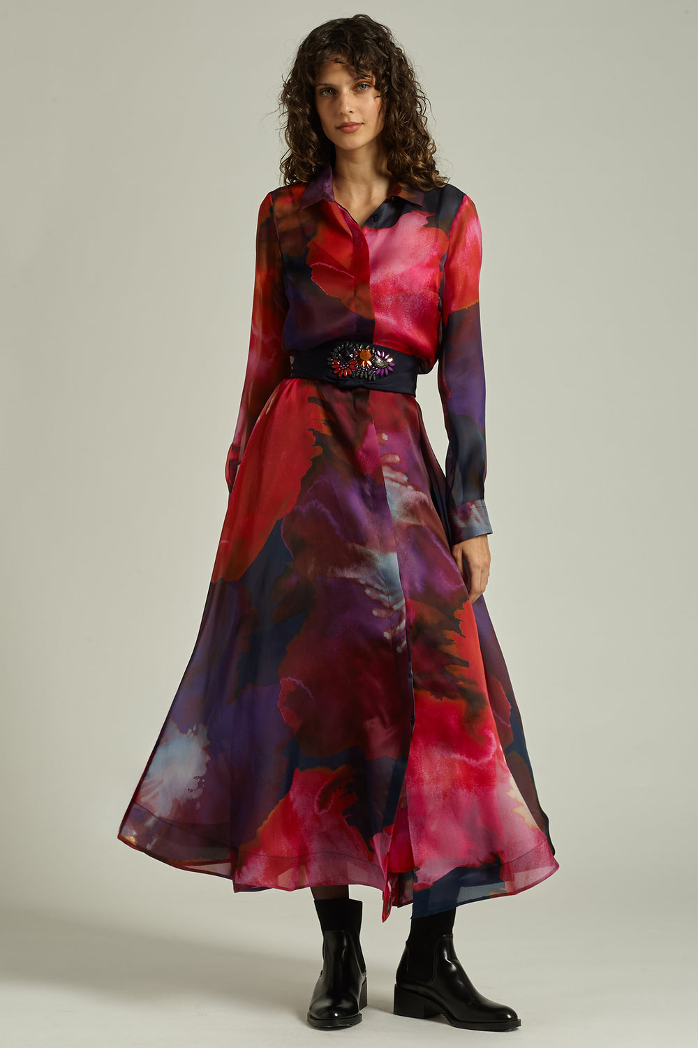 Woman wearing a colorful dress with a belt against a plain background