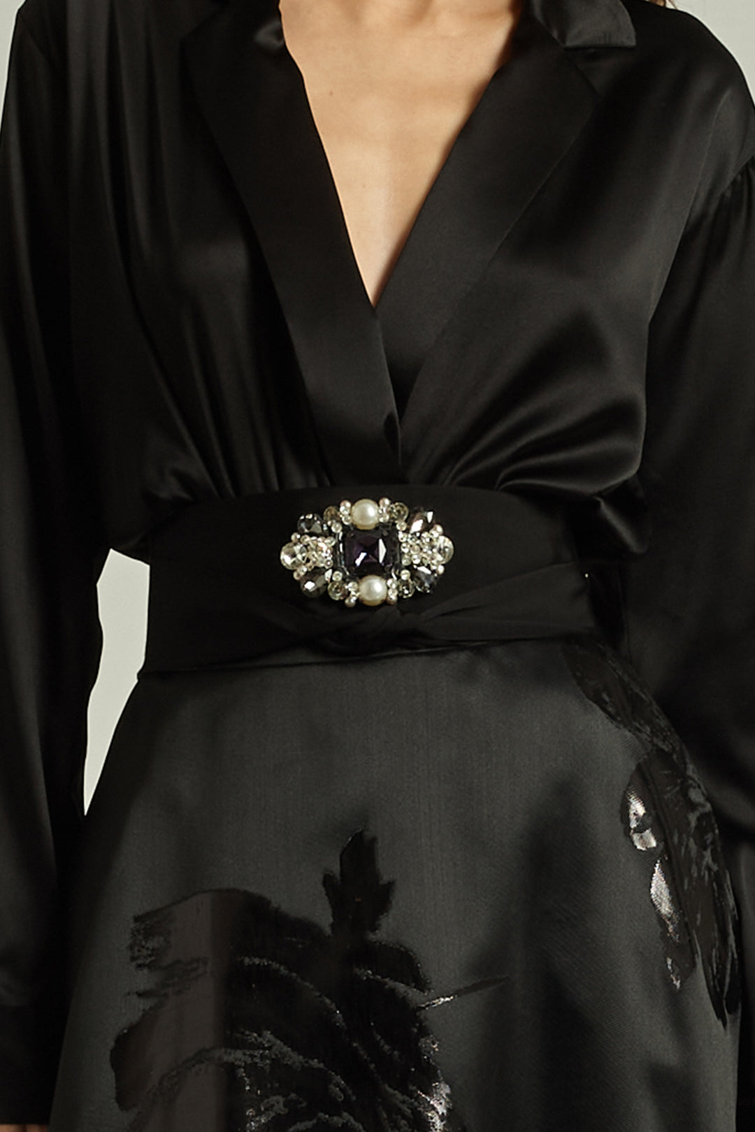Black dress with a decorative belt featuring pearls and crystals on a neutral background