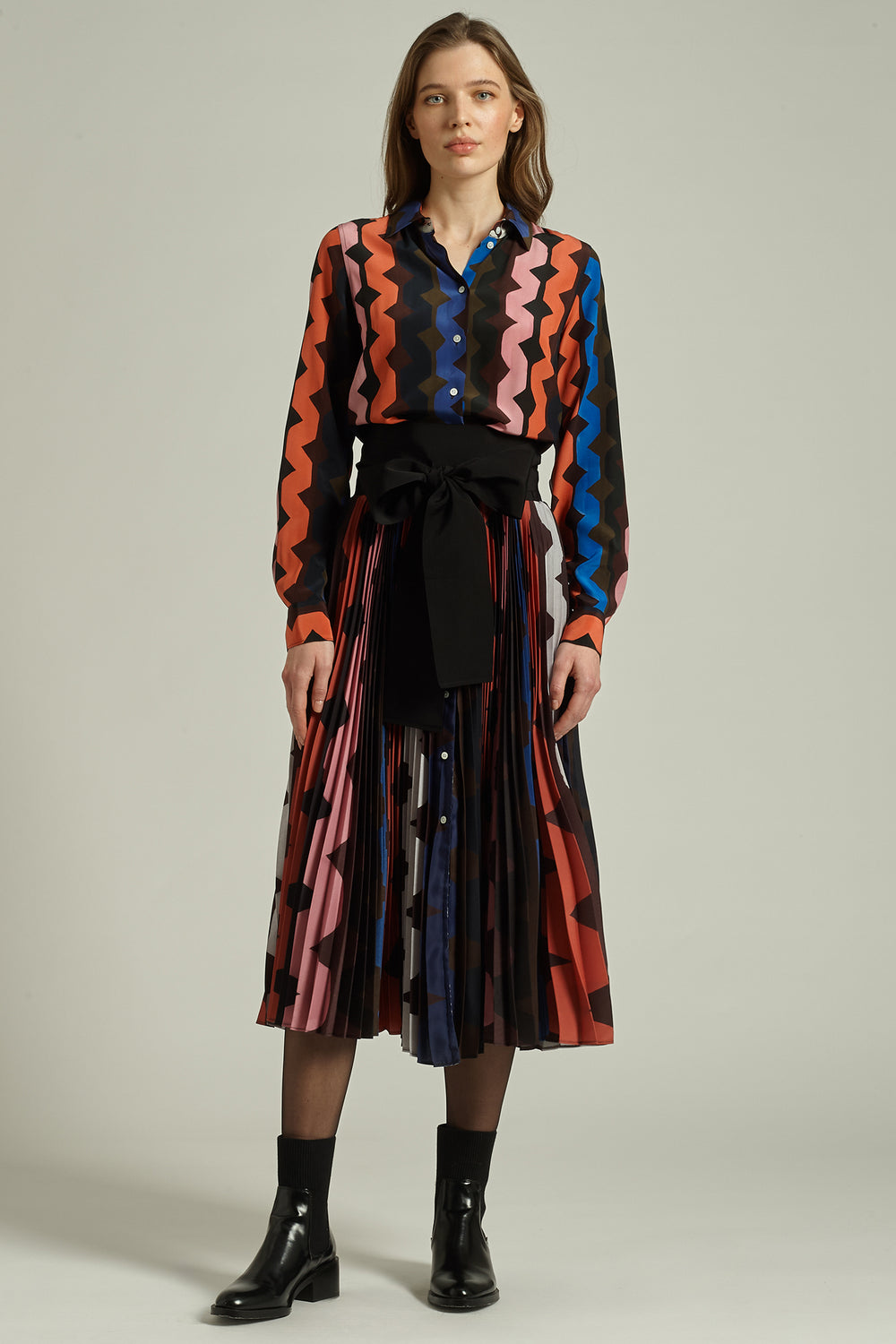 Woman wearing a colorful patterned outfit with a plain background