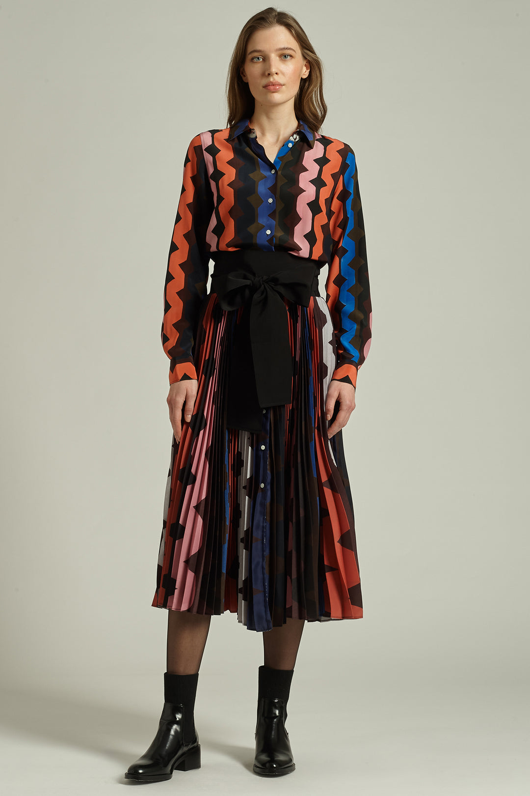 Woman wearing a colorful patterned outfit with a plain background