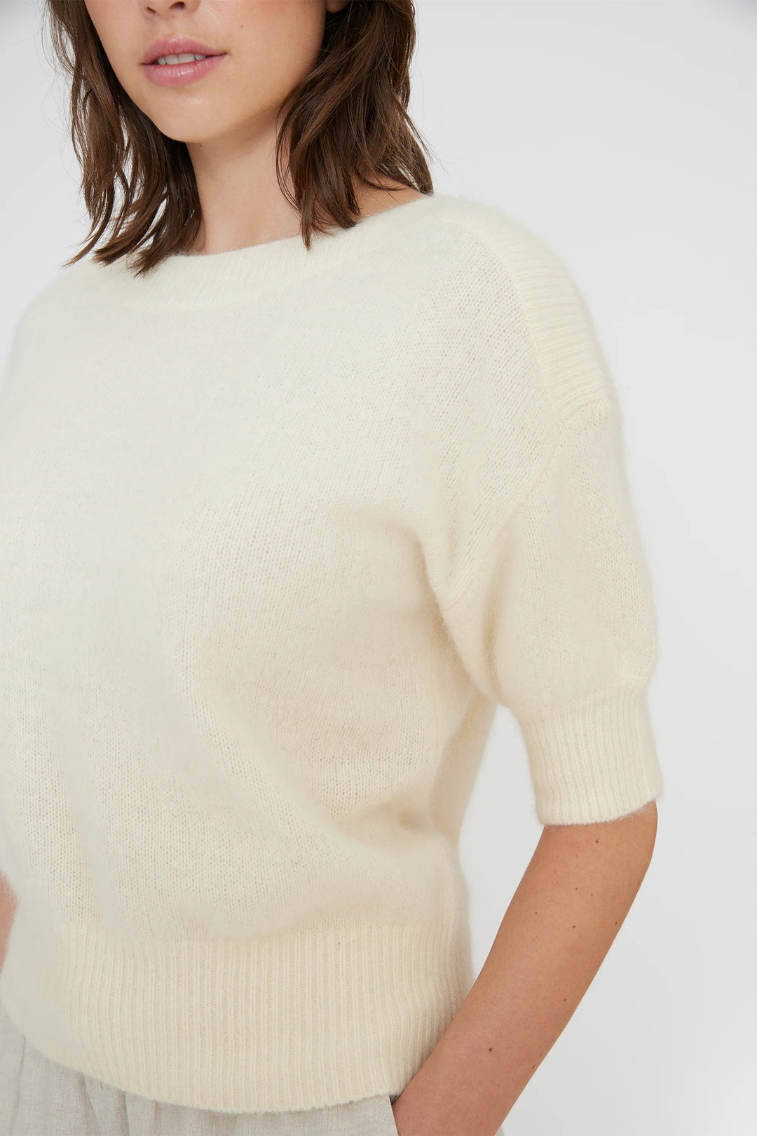 Woman wearing a light beige sweater against a white background