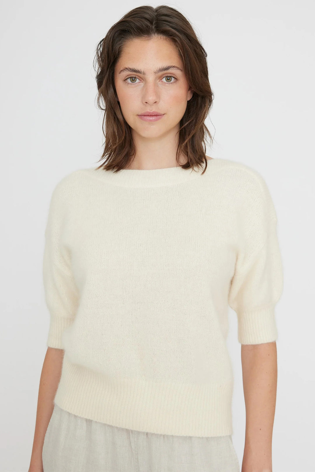 Woman wearing a light-colored sweater against a plain background