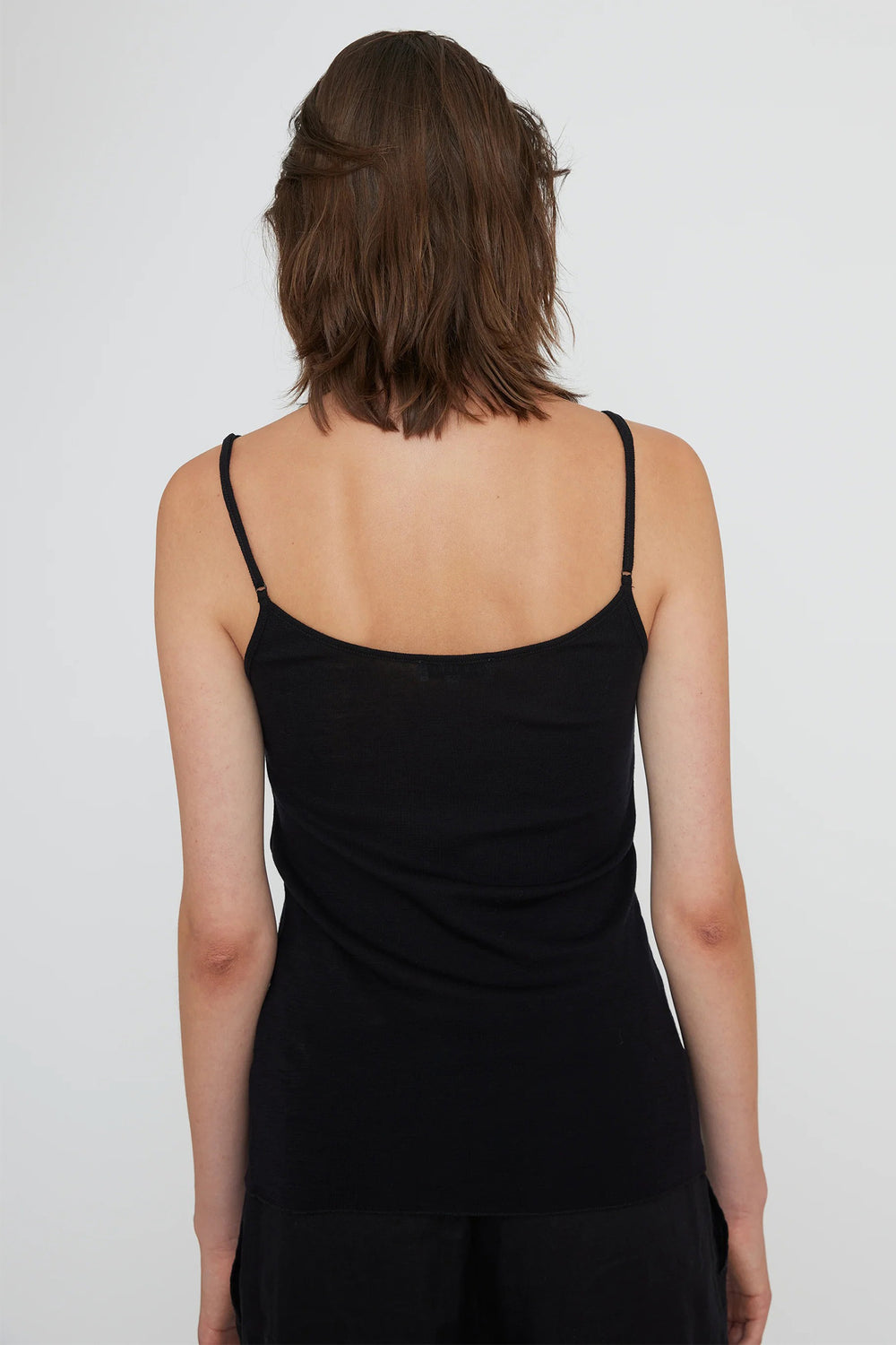 Person wearing a black slip dress against a plain background