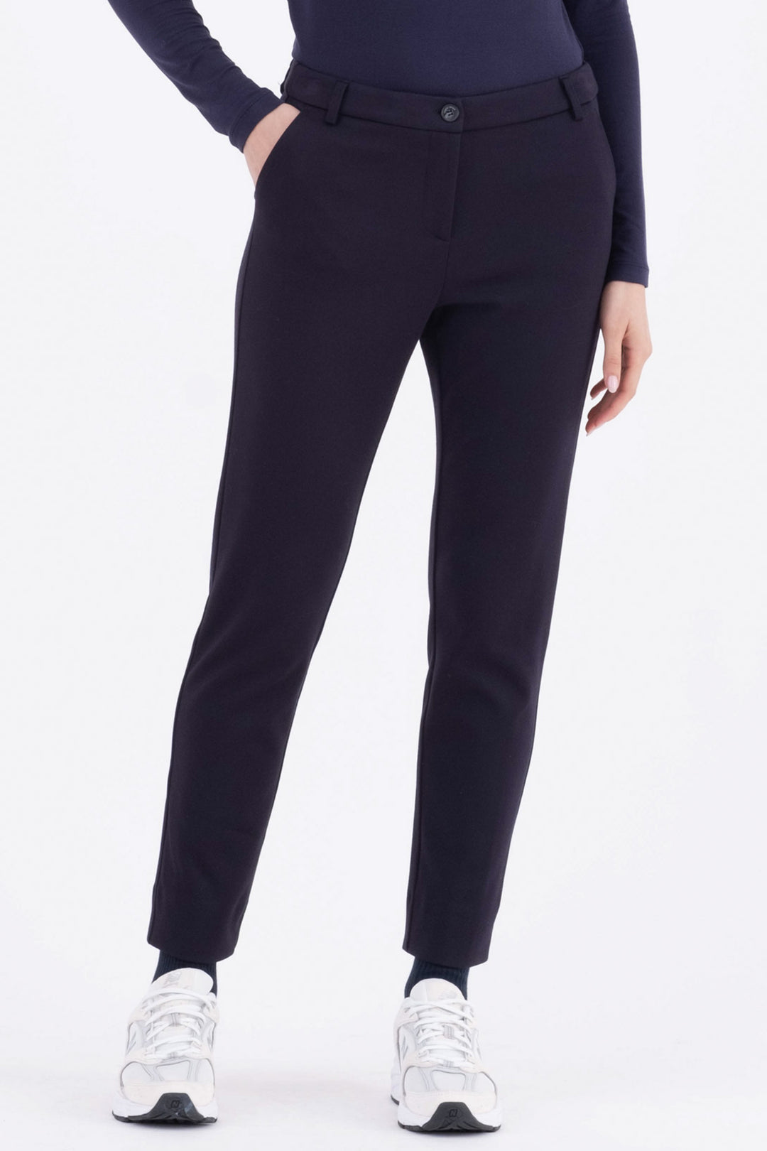 Person wearing navy pants and white sneakers on a white background